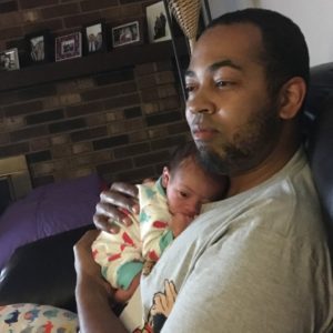 father holds very small baby.